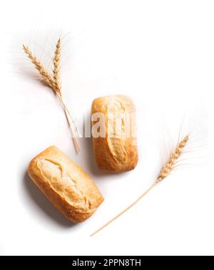 Fresh homebaked artisan bread. Two mini baguette bread and ears of wheat isolated on white background, design element. Stock Photo
