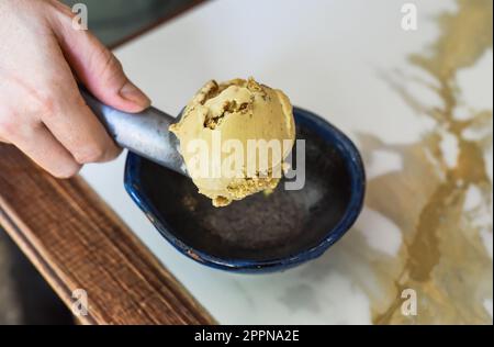 hand scooping a scoop of ice cream into a spoon in fridge Stock Photo