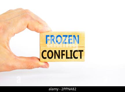 Frozen conflict symbol. Concept words Frozen conflict on beautiful wooden block. Beautiful white table white background. Businessman hand. Business an Stock Photo