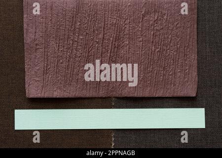 textured brown and green paper stripe on a dark brown fabric background Stock Photo