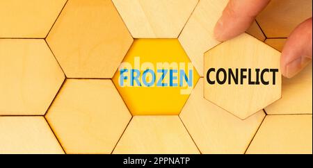 Frozen conflict symbol. Concept words Frozen conflict typed on wooden puzzles. Beautiful yellow table yellow background. Businessman hand. Business an Stock Photo