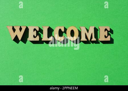 Welcome, word in wooden alphabet letters isolated on bright green background Stock Photo