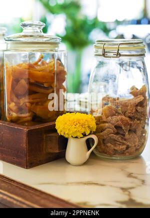 Chernobrivtsy flower near jars with crystalized dried fruits in a coffee shop Stock Photo