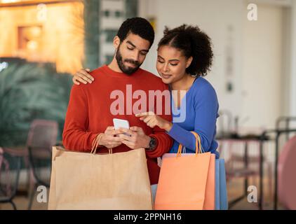 Middle Eastern Couple Using Mobile Phone Shopping Standing Outdoor Stock Photo
