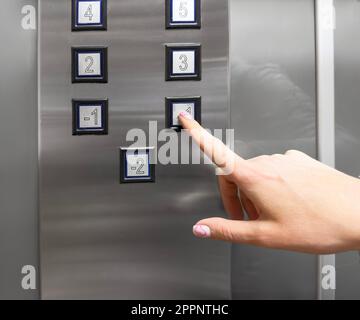 Woman hand pressing push button for elevator. Hand finger press the Elevator button. Woman using Elevator in office or apartment Stock Photo