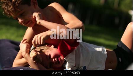 Brothers quarrel outside in backyard. Siblings fighting each other outdoors Stock Photo