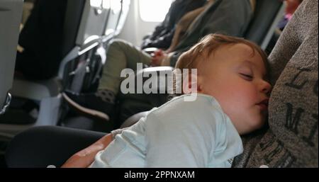 Calm sleeping baby toddler inside commercial flight. infant asleep while flying Stock Photo