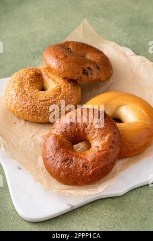 Homemade freshly baked bagels on a parchment paper ready to eat, cinnamon raisin, sesame and plain bagel Stock Photo