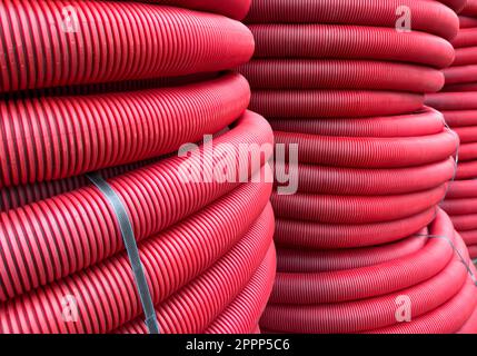 HDPE corrugated pipe texture background. Protection underground cable. Rolled up red corrugated PVC pipe. Red building pipes. Coated corrugated constr Stock Photo