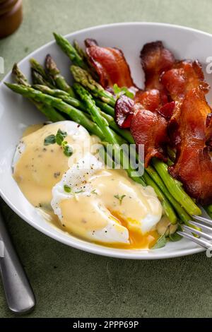 Healthy breakfast with poached eggs, bacon and asparagus served with hollandaise sauce Stock Photo