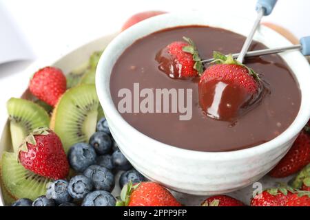Dipping strawberries into fondue pot with chocolate, closeup Stock Photo