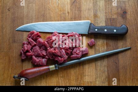 Herefordshire diced beef on a wooden table using a rustic knife and steel. Stock Photo