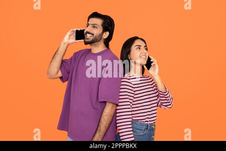 Beautiful loving indian couple using cell phones, have conversation Stock Photo