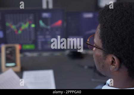 Close-up of young trader analyzing financial graphics on computers sitting at his workplace Stock Photo