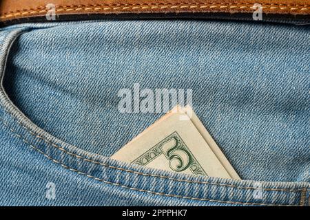Five dollar bill in the pocket of the jeans, close up Stock Photo