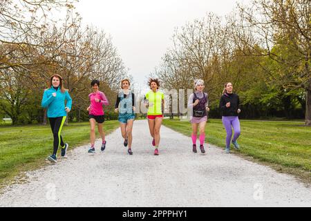 Group of female runners running in a park. Mature women exercising outdoors. Concept of wellness and body care in old age Stock Photo