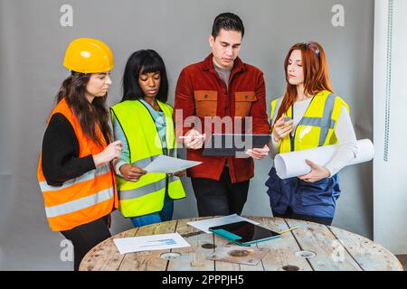 Female workers on a construction site who are confronted with the manager. Projects in hand and tablet with information. Brain storming before work Stock Photo
