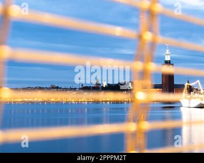 Stockholm, Sweden - 4 October, 2022: A blurred fence in front of a majestic city hall with a stunning motif stands tall, reflecting off the still wate Stock Photo