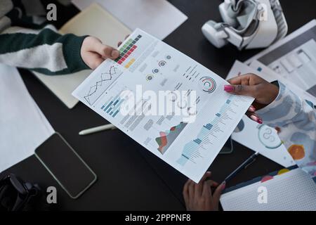 High angle view of colleagues examining document with graphs at table during meeting in office Stock Photo