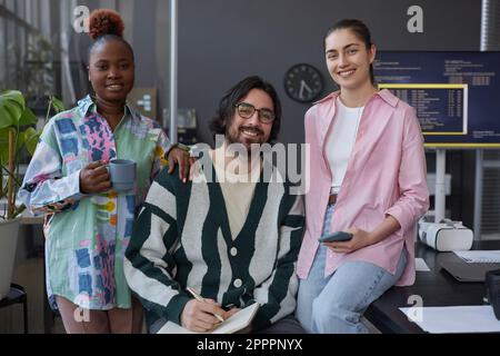 Portrait of group of programmers smiling at camera while working with new software in team in office Stock Photo