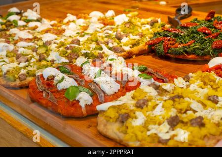 Different kinds of pizza on the wooden desk in the pizza restaurant. Stock Photo