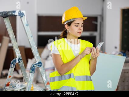 Young woman engineer using smartphone in construction site Stock Photo