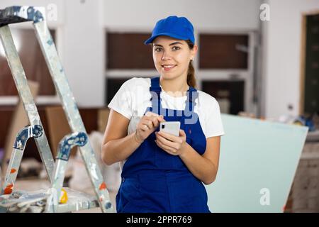 Young woman builder using smartphone in construction site Stock Photo