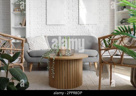 Coffee table with aroma candles and houseplant in bright living room Stock Photo