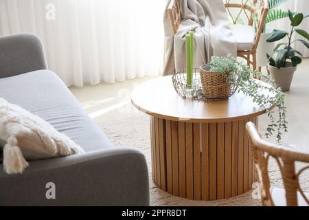 Coffee table with aroma candles and houseplant in bright living room Stock Photo