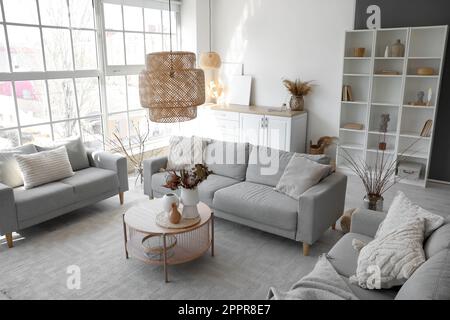 Interior of cozy living room with grey sofas and vases on coffee table Stock Photo