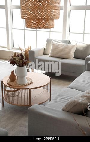Cozy grey sofas and coffee table with bouquet of dried protea flowers in living room Stock Photo