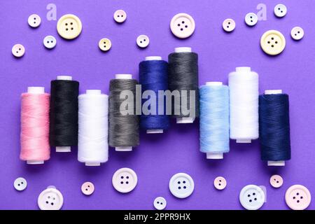 Composition with different thread spools and buttons on color background Stock Photo