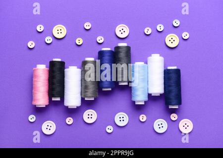 Composition with different thread spools and buttons on color background Stock Photo