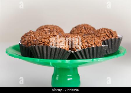 Brigadeiro (Brigadier) Traditional brazilian sweet. Chocolate candy on green support and white background. Front view. Stock Photo