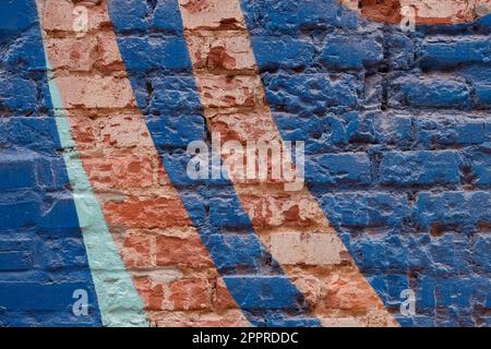 Weathered and painted brick wall with blue background and red swoops. Stock Photo