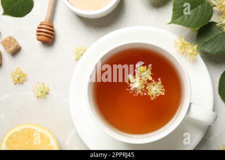 Flat lay composition with tasty tea and linden blossom on light grey marble table Stock Photo