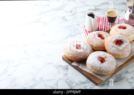 Delicious jam donuts served with coffee on white marble table. Space for text Stock Photo