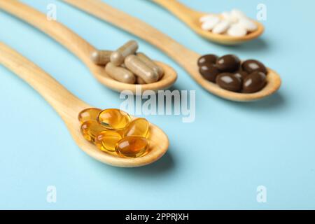 Wooden spoons with different dietary supplements on light blue background Stock Photo