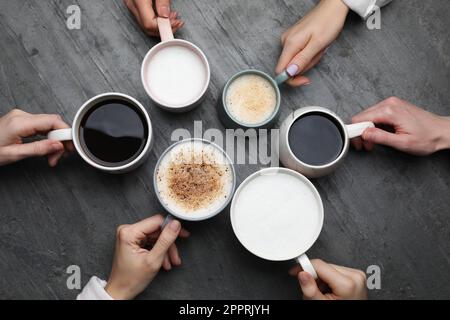 People holding different cups with aromatic hot coffee at grey table, top view Stock Photo