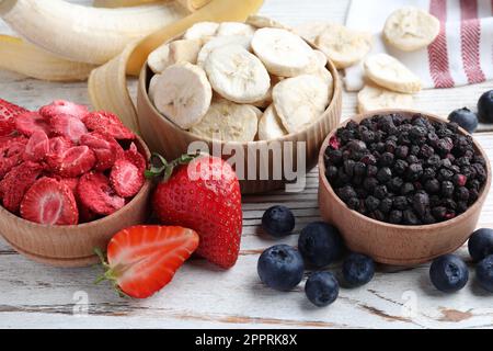 Different freeze dried and fresh fruits on white wooden table, closeup Stock Photo