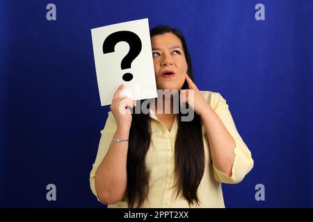 Latino adult woman shows a question mark, wonders, doubts, suspects, assumes, fears and distrusts Stock Photo