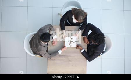top view. business colleagues collecting puzzle, sitting at the table. Stock Photo