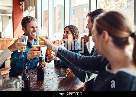 Having a pint at the bar with friends. a group of friends making a toast while enjoying themselves in a bar. Stock Photo