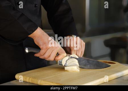 Unrecognizable man cuts onions in the kitchen Stock Photo
