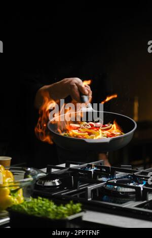 Flambering wok ingredients in a frying pan Stock Photo