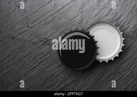Black beer caps on dark slate background or texture. Mock up design template. 3D rendering illustration. Stock Photo