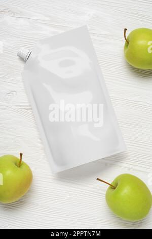 White plastic pouch bag with apples on wood table. Mock-up template for design. 3d rendering illustration. Stock Photo