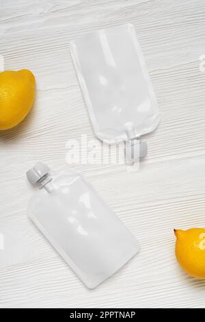 White empty plastic pouches for baby food, fruit puree on wood table. Mock-up template for design. 3d rendering illustration. Stock Photo