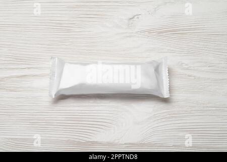 White blank chocolate bar package on the wood table. Mock-up template. Candy bar plastic wrap. Stock Photo