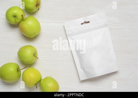 White plastic pouch bag with apples on wood table. Mock-up template for design. 3d rendering illustration. Stock Photo